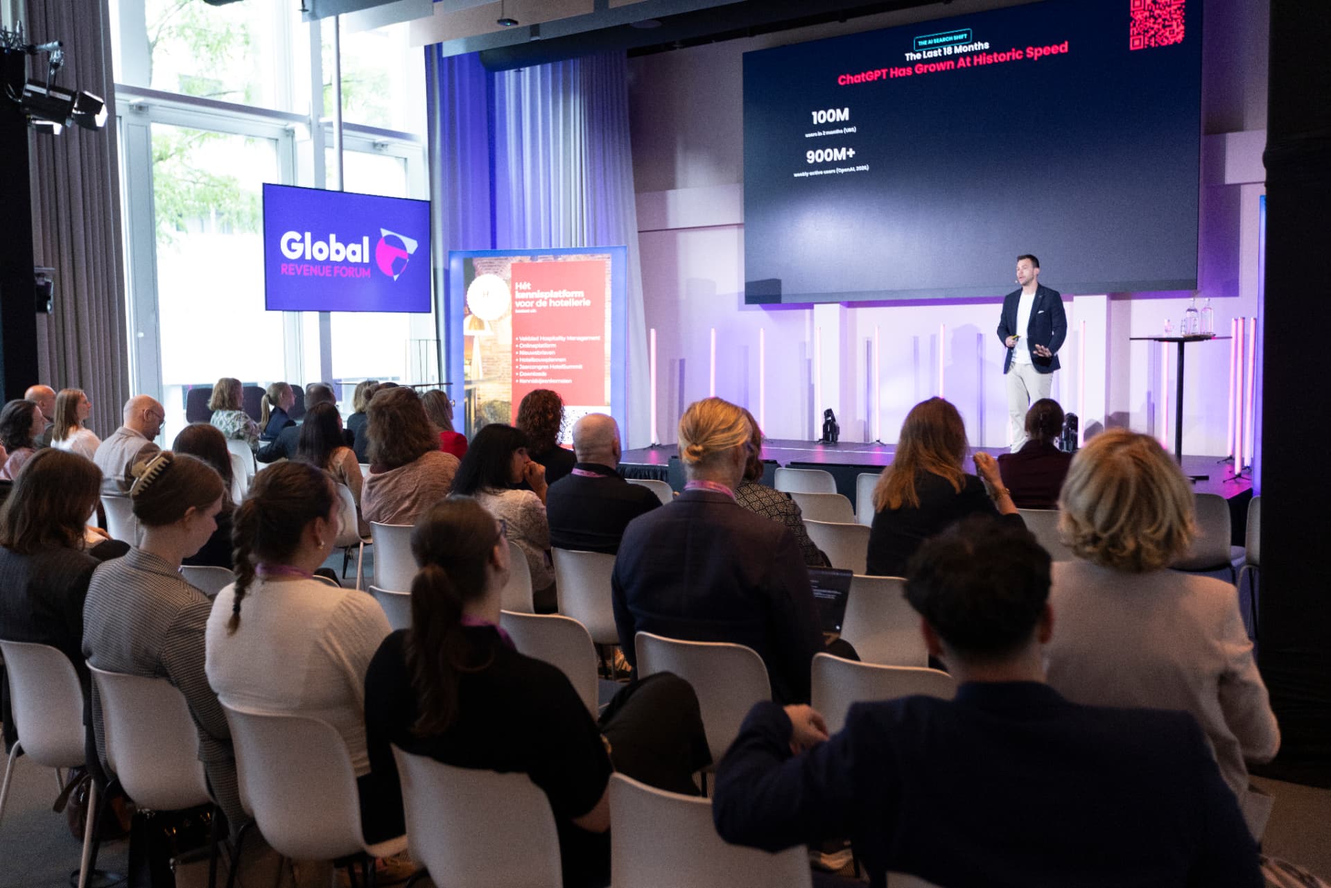 Adam Hamadache presenting on stage to an audience at a hospitality industry conference
